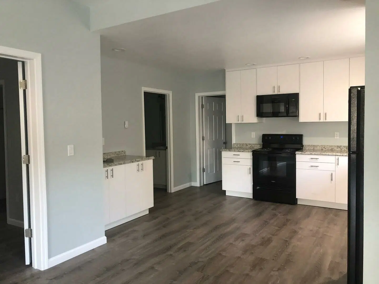 Kitchen remodel featuring white cabinetry, dark appliances, and new flooring in an updated open-concept layout.